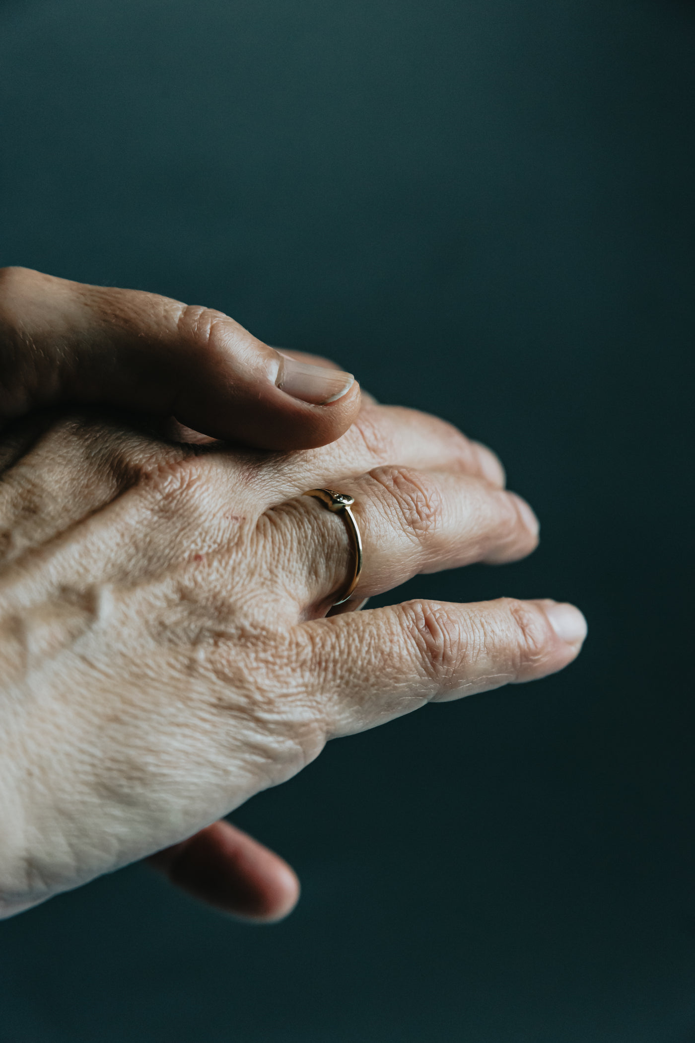 An older hand wearing a plain worn wedding band