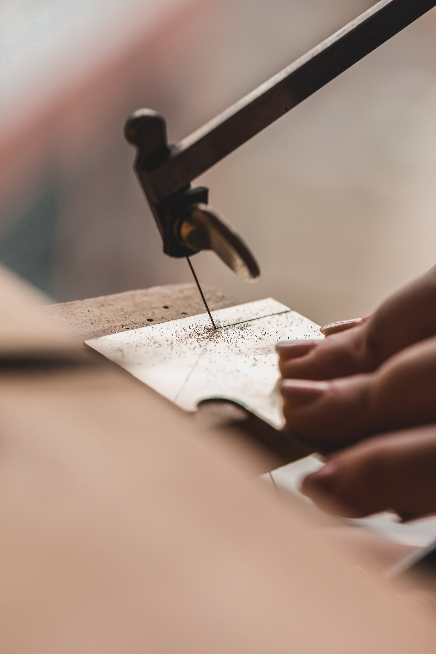 Hands sawing a sheet of metal over a bench pin