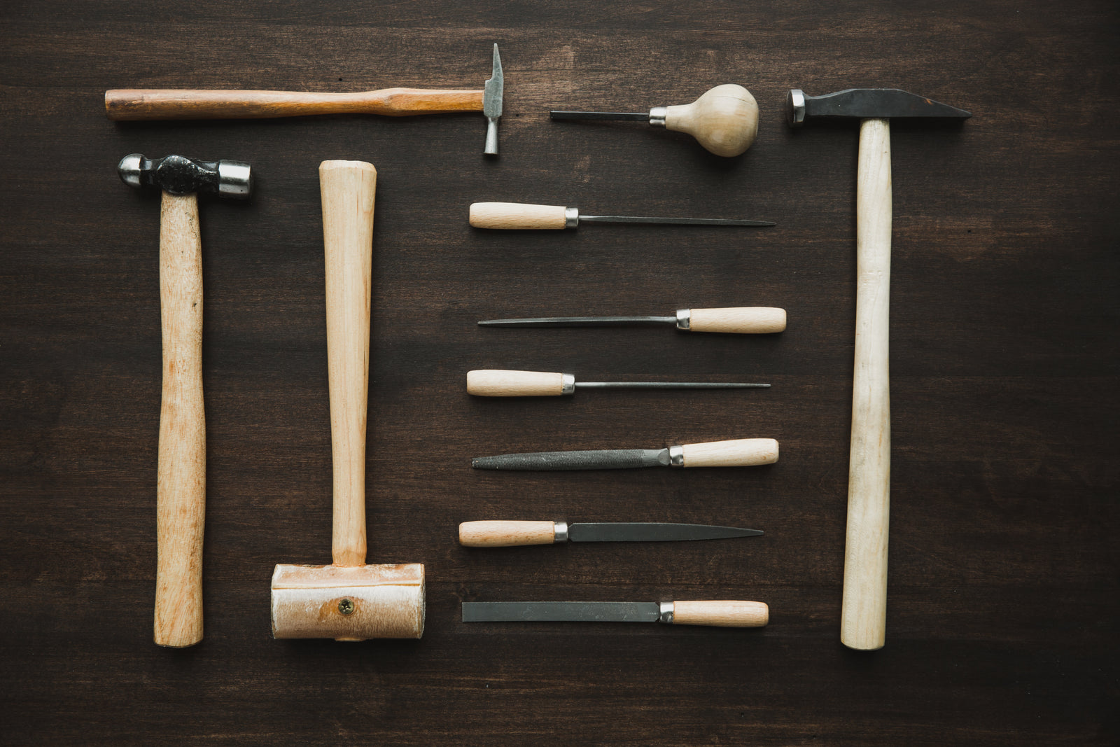 Jeweller's hammers, files and mallets arranged on a dark wooden bench