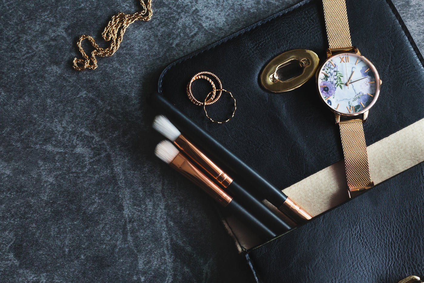 Rings, a watch and brushes arranged inside an open leather case